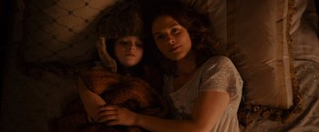 Movie still from “Winter's Tale” (2014), directed by Akiva Goldsman – A woman and a child laying in a bed together; Close Up shot, Overhead angle