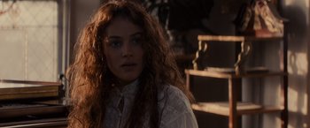 Movie still from “Winter's Tale” (2014), directed by Akiva Goldsman – A woman with long red curly hair wearing a white shirt; Close Up shot, Over the shoulder angle