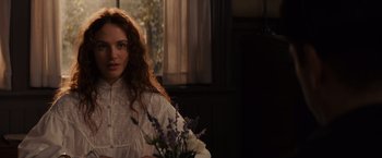 Movie still from “Winter's Tale” (2014), directed by Akiva Goldsman – A woman in a white dress holding a bouquet of flowers; Medium shot, Over the shoulder angle