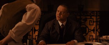 Movie still from “Winter's Tale” (2014), directed by Akiva Goldsman – A man sitting in a chair in front of a camera; Close Up shot, Over the shoulder angle