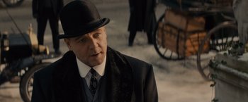 Movie still from “Winter's Tale” (2014), directed by Akiva Goldsman – A man wearing a black hat and a black suit; Close Up shot, Over the shoulder angle