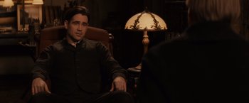 Movie still from “Winter's Tale” (2014), directed by Akiva Goldsman – A man sitting in front of a lamp in a dark room; Medium shot, Over the shoulder angle