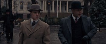 Movie still from “Winter's Tale” (2014), directed by Akiva Goldsman – Two men in suits and hats standing next to each other; Medium shot, Low angle