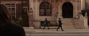 Two women walking down the sidewalk in front of a building