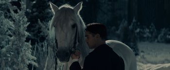Movie still from “Winter's Tale” (2014), directed by Akiva Goldsman – A man standing next to a white horse in the dark; Close Up shot, Over the shoulder angle