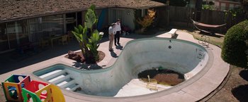 Movie still from “Wish I Was Here” (2014), directed by Zach Braff – Two men standing in front of an empty swimming pool; Extreme Wide shot, High angle