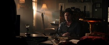 Movie still from “Wish I Was Here” (2014), directed by Zach Braff – A man sitting at a table in a dark room; Medium shot, Low angle