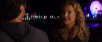 Movie still from “Wish I Was Here” (2014), directed by Zach Braff – A woman sitting in front of a man in front of a city skyline at night; Close Up shot, Over the shoulder angle