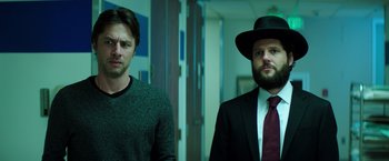 Movie still from “Wish I Was Here” (2014), directed by Zach Braff – Two men standing next to each other in front of a door; Medium shot, Low angle