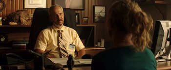 Movie still from “Wish I Was Here” (2014), directed by Zach Braff – A man sitting at a desk in front of a woman; Medium shot, Over the shoulder angle