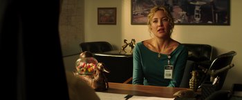 Movie still from “Wish I Was Here” (2014), directed by Zach Braff – A woman sitting in front of a table with a jar of candy; Medium shot, Over the shoulder angle