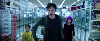 Movie still from “Wish I Was Here” (2014), directed by Zach Braff – A man is holding a jar in a store; Medium shot, Over the shoulder angle