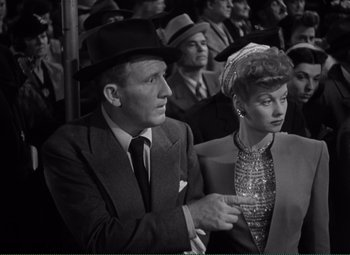 Movie still from “Without Love” (1945), directed by Harold S. Bucquet – A man and a woman are sitting together in a crowd; Medium shot, High angle