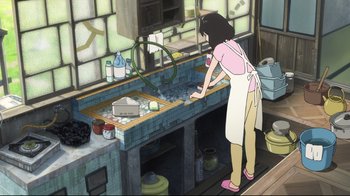 Movie still from “Wolf Children” (2012), directed by Mamoru Hosoda – An animated woman in a pink shirt and white apron cooking in a kitchen; Wide shot, High angle
