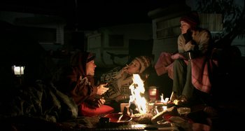 Movie still from “Wolf Creek” (2005), directed by Greg McLean – A group of people sitting around a fire at night; Wide shot, Low angle