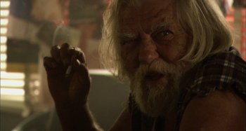 Movie still from “Wolf Creek” (2005), directed by Greg McLean – An old man smoking a cigarette while looking at the camera; Close Up shot, Over the shoulder angle