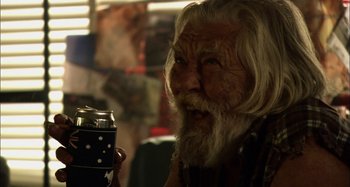 Movie still from “Wolf Creek” (2005), directed by Greg McLean – An old man holding a can of soda in his hand; Close Up shot, Over the shoulder angle