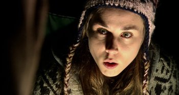 Movie still from “Wolf Creek” (2005), directed by Greg McLean – A young woman with long brown hair wearing a knitted hat; Close Up shot, Overhead angle