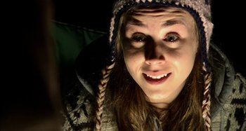 Movie still from “Wolf Creek” (2005), directed by Greg McLean – A woman wearing a knitted hat and smiling for the camera; Close Up shot, Overhead angle