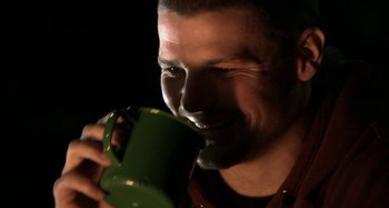 Movie still from “Wolf Creek” (2005), directed by Greg McLean – A person drinking from a mug; Close Up shot, High angle