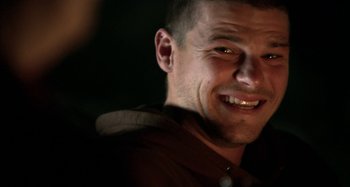 Movie still from “Wolf Creek” (2005), directed by Greg McLean – A person smiling for the camera; Close Up shot, Over the shoulder angle