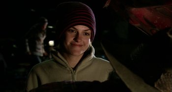 Movie still from “Wolf Creek” (2005), directed by Greg McLean – A young woman wearing a striped hat smiling for the camera; Close Up shot, Over the shoulder angle