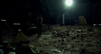 Movie still from “Wolf Creek” (2005), directed by Greg McLean – A person standing in the dirt at night with a flashlight; Extreme Wide shot, High angle