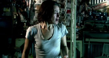 Movie still from “Wolf Creek” (2005), directed by Greg McLean – A woman in a white t - shirt standing in a room; Medium shot, Over the shoulder angle