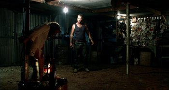 Movie still from “Wolf Creek” (2005), directed by Greg McLean – A man standing in the dark in a room; Wide shot, Over the shoulder angle