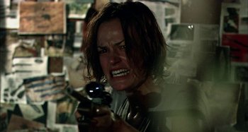 Movie still from “Wolf Creek” (2005), directed by Greg McLean – A person holding a gun in a room; Close Up shot, Over the shoulder angle