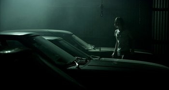 Movie still from “Wolf Creek” (2005), directed by Greg McLean – A woman standing next to a row of parked cars; Wide shot, Low angle
