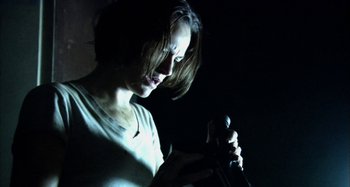 Movie still from “Wolf Creek” (2005), directed by Greg McLean – A woman holding a microphone and looking at her cell phone; Close Up shot, Low angle