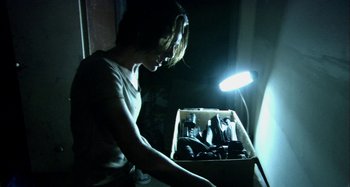 Movie still from “Wolf Creek” (2005), directed by Greg McLean – A woman holding a box full of beer bottles; Medium shot, Low angle
