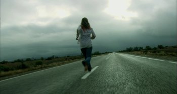 Movie still from “Wolf Creek” (2005), directed by Greg McLean – A woman running down the middle of the road; Wide shot, Low angle