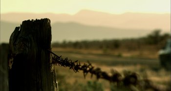 Movie still from “Wolf Creek” (2005), directed by Greg McLean – A barbed - wire fence in a field; Extreme Close Up shot, Low angle