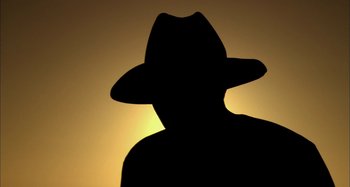 Movie still from “Wolf Creek” (2005), directed by Greg McLean – A man wearing a hat is standing in front of the sun; Extreme Close Up shot, Low angle