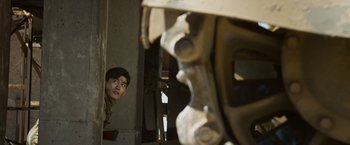 Movie still from “Wolf Warrior 2” (2017), directed by Jing Wu – A young man looking out of a window at a building; Medium shot, Over the shoulder angle