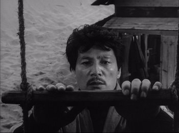 A black - and - white photo of a man holding onto a pole