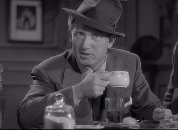 Movie still from “Woman of the Year” (1942), directed by George Stevens – A black and white photo of a man holding a coffee cup; Close Up shot, Low angle