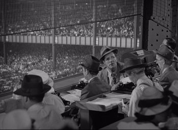 Movie still from “Woman of the Year” (1942), directed by George Stevens – A group of men sitting at a table in a stadium; Wide shot, High angle