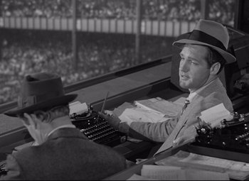 Movie still from “Woman of the Year” (1942), directed by George Stevens – An old photo of a man sitting at a desk with a typewriter; Medium shot, High angle