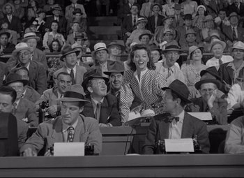 Movie still from “Woman of the Year” (1942), directed by George Stevens – A group of men and women sitting in a stadium; Medium shot, High angle