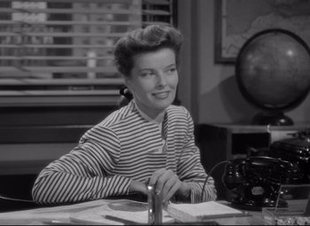 Movie still from “Woman of the Year” (1942), directed by George Stevens – A woman sitting at a table in a room; Medium shot, High angle