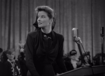Movie still from “Woman of the Year” (1942), directed by George Stevens – An old black and white photo of a woman speaking at a podium; Close Up shot, Low angle