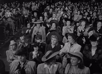 Movie still from “Woman of the Year” (1942), directed by George Stevens – A group of people sitting in a crowd wearing hats; Wide shot, High angle