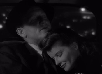Movie still from “Woman of the Year” (1942), directed by George Stevens – A man and a woman laying in a car together; Close Up shot, High angle
