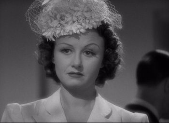 Movie still from “Woman of the Year” (1942), directed by George Stevens – A woman wearing a hat with flowers on top of her head; Close Up shot, Over the shoulder angle
