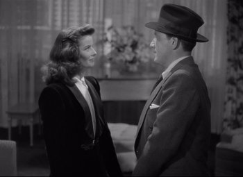 Movie still from “Woman of the Year” (1942), directed by George Stevens – A man and a woman standing next to each other in a room; Medium shot, Over the shoulder angle