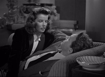 Movie still from “Woman of the Year” (1942), directed by George Stevens – An old photo of a man and a woman sitting on a couch; Medium shot, High angle