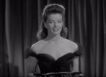 Movie still from “Woman of the Year” (1942), directed by George Stevens – A black and white photo of a woman in a black dress; Medium shot, Low angle